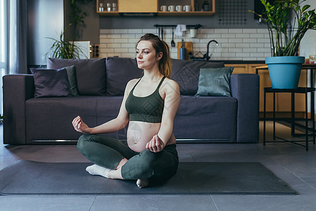 怀孕的美孕妇在家做瑜伽 坐在莲花姿势的运动垫子上享受练习平衡身体训练眼睛药品冥想健身房成人图片