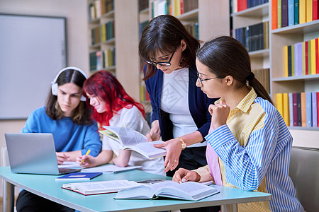 青少年学生群体和在图书馆书桌上的师范学习中学女士老师导师笔记本考试团体桌子电脑男生图片