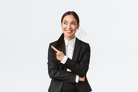 成功乐观微笑的亚洲女经理 穿着西装的女商务人士看起来自信 笑着指着左上角 站在白色背景上高兴工作建筑师幸福工作室员工商业企业家电图片