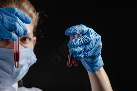 一位女性病毒学家在黑色背景下处理血液试管 一名护士手里拿着采血管 大流行性疫苗的工作概念图片