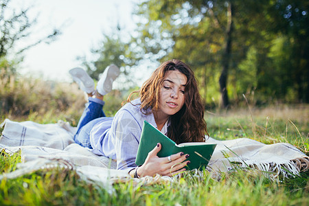 美丽的年轻女学生会读书 读书 躺在自然中的草地上摄影幸福青少年大学微笑文化女性隐藏快乐音乐图片