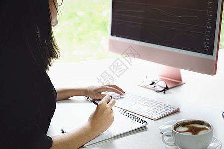 新的正常的自营职业妇女手持笔用笔记本和电脑笔记本交换股票 以牟利 买进和销售图片
