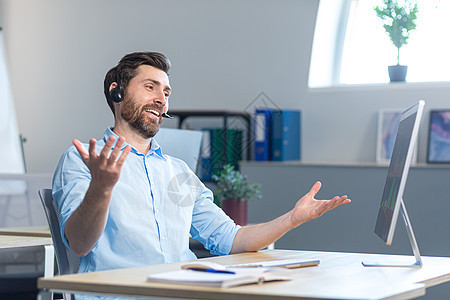 一个快乐惊喜的呼叫中心员工在办公室工作 佩戴头盔 进行视频通话推销男性商业麦克风人士幸福男人电话惊愕客户图片