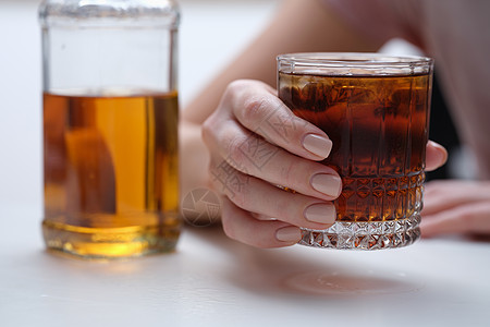 女人手握着威士忌或白兰地酒杯欲望瓶子情怀桌子离婚饮料疾病持有女性酗酒图片