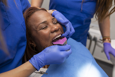 在牙科诊所放置一个印托盘; 将口腔医生用手贴近牙医的手图片