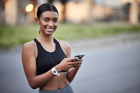 一个运动的年轻女子在户外锻炼时 使用手机的肖像 她是个体育女郎图片