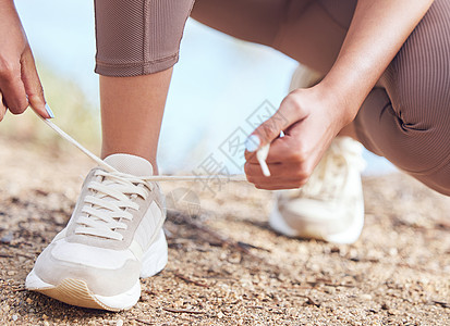 今天我还有目标要完成 近距离拍摄一个不知名的女人 在户外锻炼时绑着她的鞋带的图片