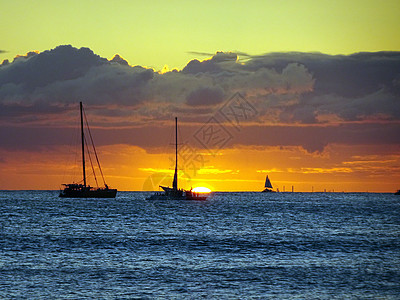 在日落的Waikiki太平洋水域上的船地平线太阳岛屿波浪橙子海滩双体反射海洋旅行图片