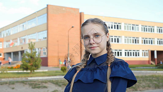 一个十几岁的女孩 在学校门口戴眼镜手指学习幸福游客女性眼镜学生电脑背包女士图片