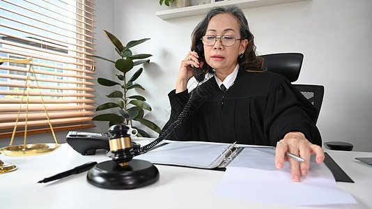 女法官或身着睡袍制服 在办公室工作并有合同文件的成年女法官或律师图片