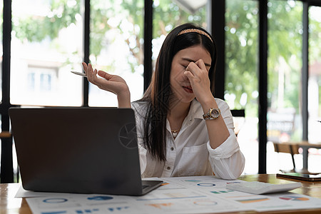 在笔记本电脑上工作的压力很大的商业妇女 看着忧心忡忡 疲劳和不堪重负的眼神去计算图片