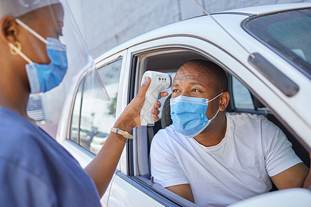 驾车通过为驾车或旅行的人提供 covid 筛选或测试服务 戴面具的黑人在车里用红外线温度计作为冠状病毒协议进行体温测试图片