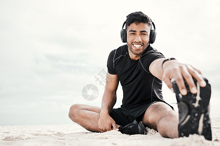 右侧的播放列表会让你心情好一点 一个年轻人在沙滩上伸展时 戴着耳机穿戴耳机图片