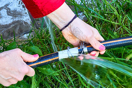 一位年轻女子的手 在花园里修补自来水管灌溉龙头溪流压力软管管子流动环境技术配件图片