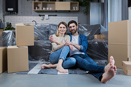 在家快乐的年轻夫妇男女 坐在沙发上 在新租来的公寓里房子新生活家庭微笑地面夫妻抵押享受搬迁幸福图片
