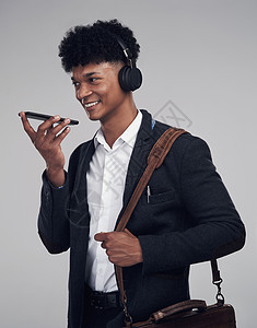 工作室拍摄一名年轻商务人士在灰色背景下使用智能手机和耳机的画面 这名青年商务人士被拍到了一张电影片子图片