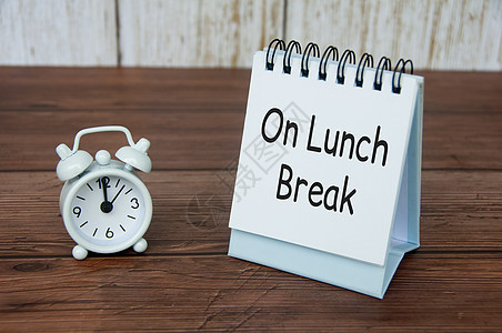 中午午间休息时 在白桌日历上的午餐课外文字 闹钟敲响时间为下午12点图片