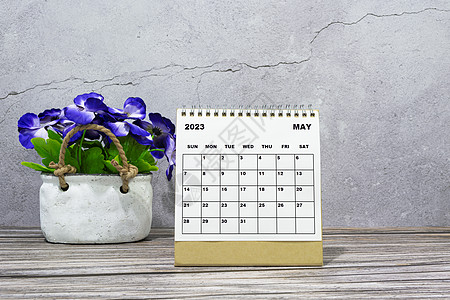 2023年5月的办公桌日历 在配有陶瓷工厂的木制桌子上图片