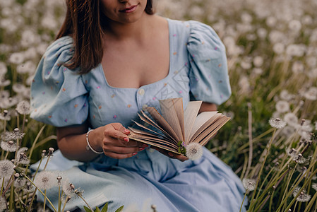 女人翻阅纸质书的页面 穿着复古或复古连衣裙的女士坐在大自然中阅读有趣的小说 大气的场面 教育 爱好 娱乐理念创造力手指字典车削魔背景图片