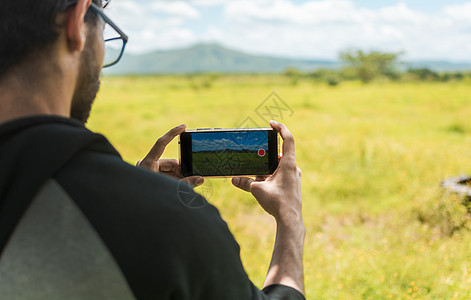 用手机拍摄风景照片的男人手的特写 一个人用手机拍田地的后视图 一个男人拍田地的后视图图片