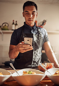 可以为您的新闻提要增添趣味的东西 一个年轻人用智能手机拍摄他在家准备的健康餐点图片