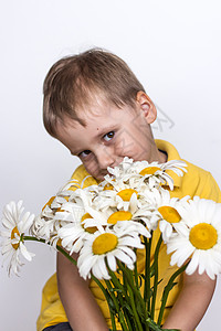 一个可爱的男孩 带着一束美丽的大雏菊 一个孩子的肖像 有趣而可爱的面部表情 选择性的焦点幸福乐趣家庭日阳光微笑金发女郎忠诚礼物快图片