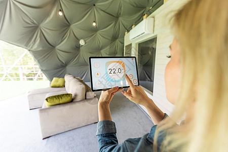 年轻女性用智能手机和数字触摸屏幕板控制温度 在智能家庭进行供暖控制的概念 笑声加热电脑自动化客厅活力智力房子监控界面互联网图片