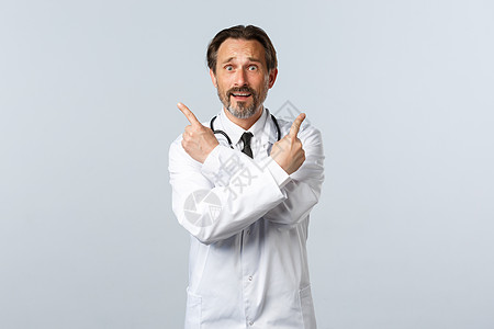 Covid19 冠状病毒爆发 保健工作者和大流行病概念 穿着白大衣的犹豫不安的男性医生 在变体上指手指侧角 要求帮助选择擦洗实习图片