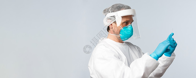 Covid19 预防病毒 医护人员和疫苗接种概念 医生在个人防护设备中用冠状病毒疫苗填充注射器治疗病人的侧面照片男人隔离急诊室防图片