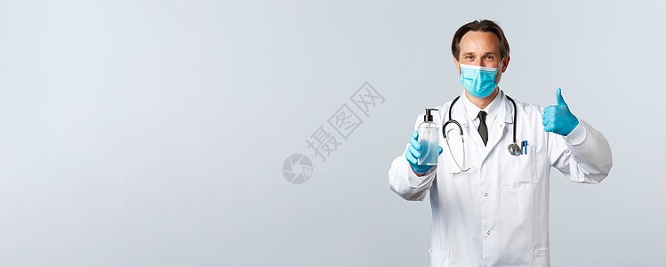 Covid19 预防病毒 医护人员和疫苗接种概念 戴医用口罩和手套的满意医生赞同 推荐洗手液 白色背景外科感染实验室消毒男人实习图片