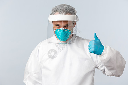 Covid19 预防病毒 医护人员和疫苗接种概念 自信的医生在个人防护设备中与冠状病毒患者一起工作 竖起大拇指 确保一切都好急诊图片