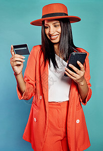 快乐和兴奋的女性网上购物 用信用卡购买或通过电话支付账单 孤立开朗的女士在网站上购物 站在蓝色复制空间背景前图片