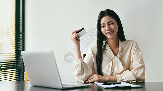 幸福的年轻妇女持有信用卡和使用笔记本电脑在网上付款 在线购物 电子商务概念和网络购物;以及图片