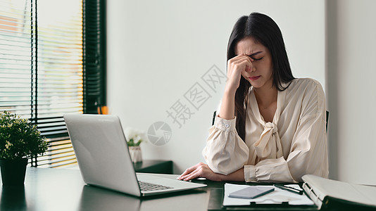 劳累过度的女企业家按摩鼻梁 解决商业问题 情绪压力 工作压力概念图片