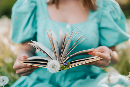 女人翻着旧纸质书 穿着复古或复古连衣裙的女士坐在大自然中阅读有趣的小说 大气的场面 教育 爱好 娱乐理念背景图片