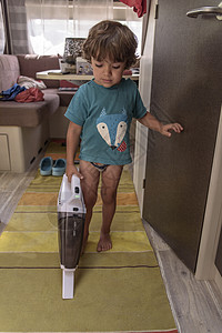 一个可爱的小男孩在度假时给大篷车吸尘 一个可爱的男孩正在清洁大篷车公寓主妇地面家政童年工作清洁工卫生房子女士图片