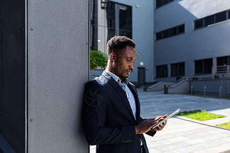 从事正式商业诉讼的非洲裔美国青年商务人士与平板电脑公司并肩工作男人经纪人市中心雇主套装手机企业家男性街道药片图片