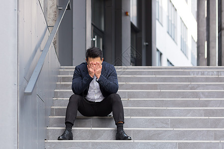 办公室附近楼梯上坐着的亚洲商务人士头痛得要命疾病震惊企业家悲伤男人压力失败职业焦虑商务图片