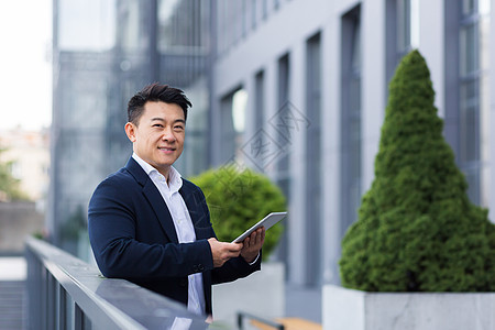 欢乐快乐的亚洲人老板从现代办公室附近的平板电脑上读到消息项目创新网站商务工作职业药片男人工具管理人员图片