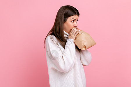 神经紧张的女孩的侧面观点 呼吸在纸袋里 改善健康状况 克服压力图片