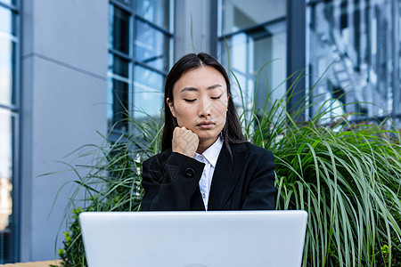 坐在办公室附近的一张长椅上 从事笔记本电脑工作的可悲和沉痛的商业妇女危机女士商务思维压力女孩挫折经理自由职业者人士图片