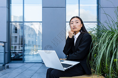 坐在办公室附近的一张长椅上 从事笔记本电脑工作的可悲和沉痛的商业妇女挫折桌子思维压力危机生意经理人士自由职业者商务图片