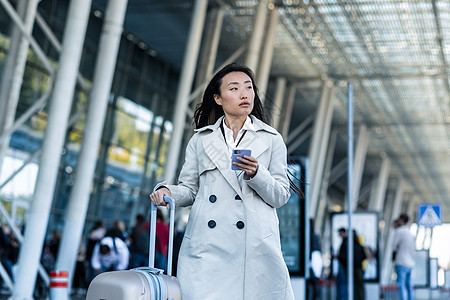 在机场附近 美丽的亚洲妇女使用电话申请在线订票的电话应用程序航空公司乘客女孩手机桌子商业人士航班商务手提箱图片