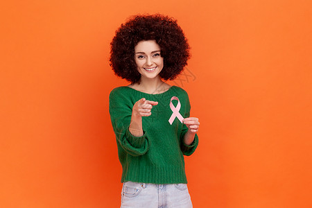 带着非洲发型的笑女人穿着绿色随身毛衣 展示了乳癌意识的象征物 她很生气 (笑声)图片