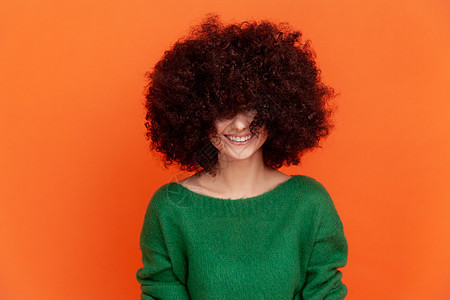 快乐的非洲发型女性穿着绿色便衣毛衣 长着毛发 听闻美容师 带着牙笑装扮图片