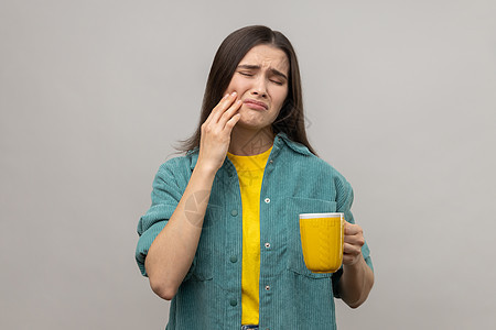 女人在喝热茶后站着摸他的脸颊 因为牙疼痛图片