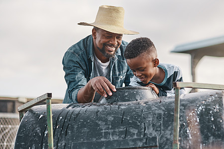 在轨道上乘坐拖拉机一天胜过一天 一个成熟的男人帮助他可爱的儿子在农场骑拖拉机图片
