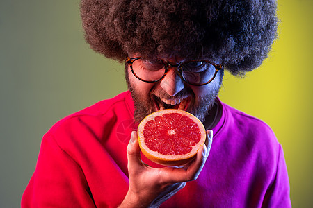 饥饿的时髦男子与非洲发型 咬葡萄汁 看水果疯狂的表情图片