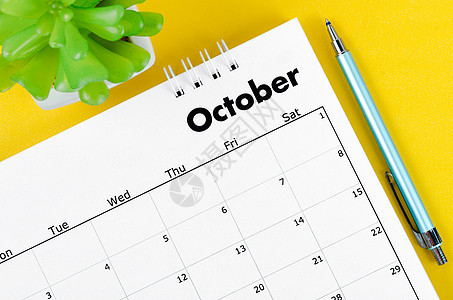 2022年10月的案头日历和笔 还有黄色背景的植物锅笔记日记季节会议数字规划师商业假期桌子桌面图片