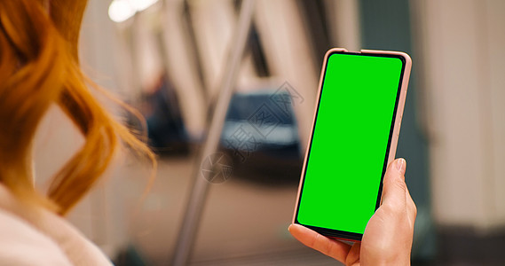 女性在公共交通中观看绿色屏幕电话 闭路和近距离图片